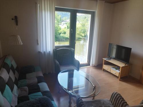 a living room with a glass table and a tv at Ferienwohnung Mila in Obernhof