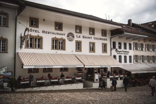 a large white building with people standing outside of it at Le Saint Georges in Gruyères