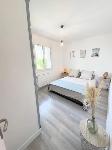 une chambre blanche avec un lit et une table dans l'établissement Villa Safran, à Colombey-les-Deux-Églises