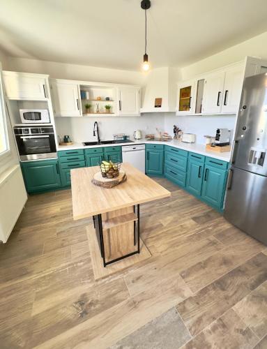 une cuisine avec des placards bleus et une table en bois dans l'établissement Villa Safran, à Colombey-les-Deux-Églises