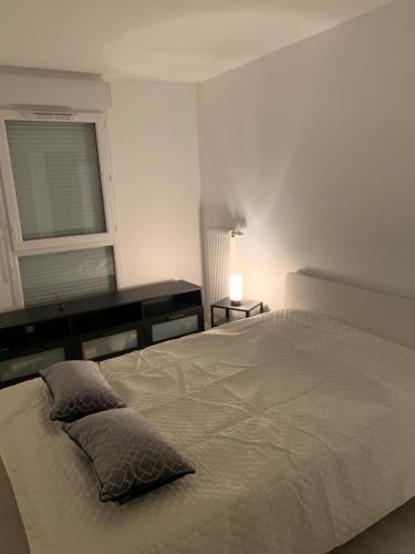 une chambre blanche avec un grand lit et une fenêtre dans l'établissement Appartement moderne, à Thiais