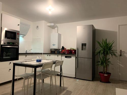 une cuisine avec une table, des chaises et un réfrigérateur dans l'établissement Appartement moderne, à Thiais