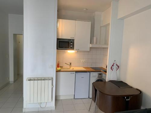 une petite cuisine avec des armoires blanches et une table dans l'établissement Charming studio Paris City Center - Maubert Mutualité, à Paris