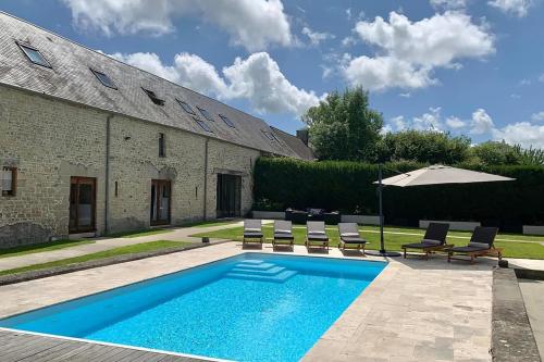 - une piscine avec des chaises et un parasol à côté d'un bâtiment dans l'établissement Le Pressoir de la Vieville, Gite St Exupery, à Mandeville-en-Bessin