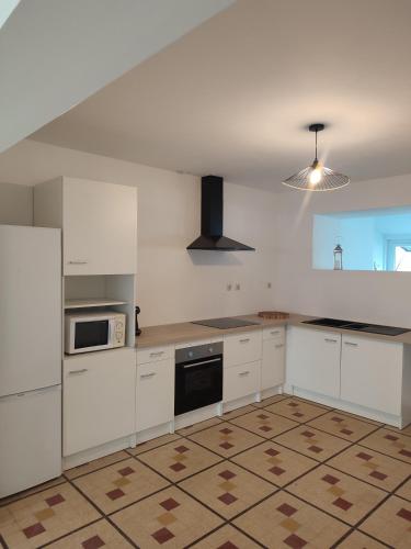 une cuisine vide avec des armoires blanches et un réfrigérateur dans l'établissement Au coeur de l'occitanie, à Cuq