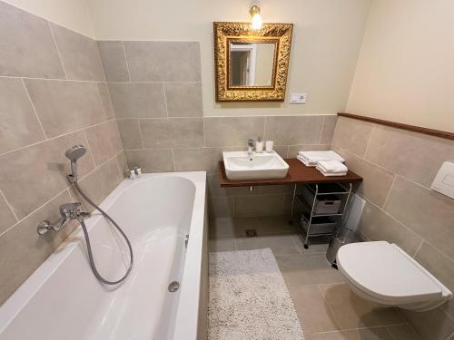 a bathroom with a tub and a toilet and a sink at Ēdoles Pils in Ēdole