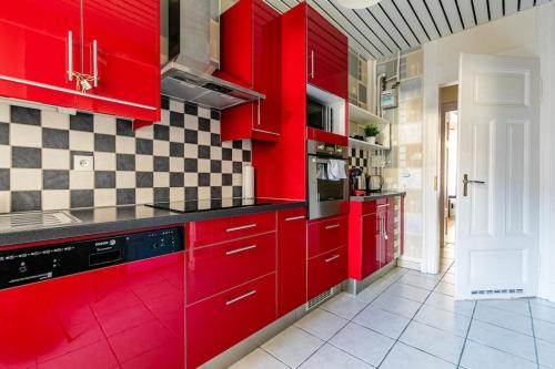 - une cuisine rouge avec des placards rouges dans une pièce dans l'établissement La Galerie Alsacienne Parking public gratuit, à Strasbourg