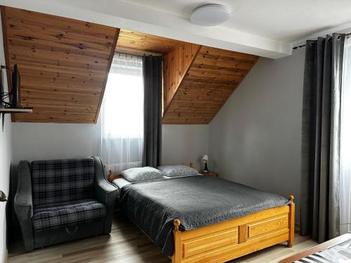 a bedroom with a bed and a chair at Odyseusz Jastarnia in Jastarnia