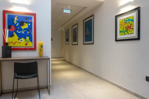 a hallway with a chair and paintings on the wall at Hotel Kuma in San Giuseppe