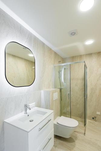 a bathroom with a sink and a toilet and a mirror at Luxury Apartment - PERLIUKAS in Palanga
