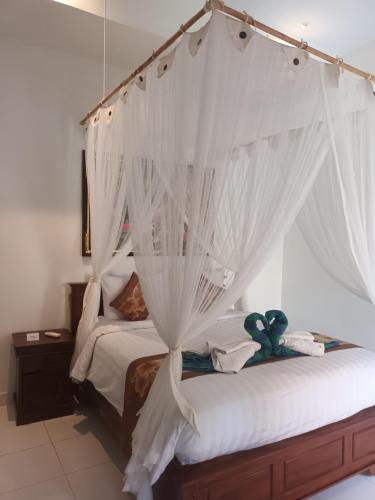 una camera con letto a baldacchino e tende bianche di Isola D'oro lembongan a Nusa Lembongan