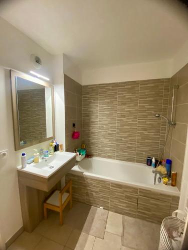 une salle de bain avec une baignoire, un lavabo et un miroir dans l'établissement Super logement à voir, à Sevran