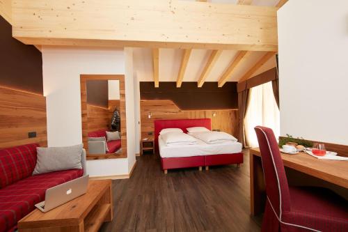 a bedroom with a bed and a red couch at Hotel Valacia in Pozza di Fassa