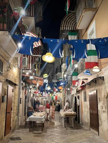 an alley with flags and people in a street at La Casa delle Tradizioni in Bari
