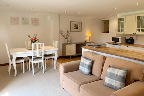 un salon et une cuisine avec un canapé et une table dans l'établissement Le Pressoir de la Vieville, Gite Renoir, à Mandeville-en-Bessin