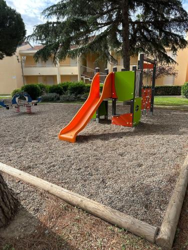 une aire de jeux avec un toboggan dans un parc dans l'établissement Appartements canet en Roussillon, à Canet