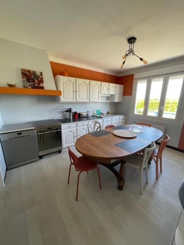 une cuisine avec une table en bois et une table et des chaises dans l'établissement Maison location saisonniere, à Trouguennour