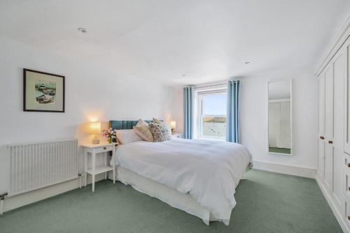 a white bedroom with a bed and a window at N ° 42 The Salcombe in Salcombe