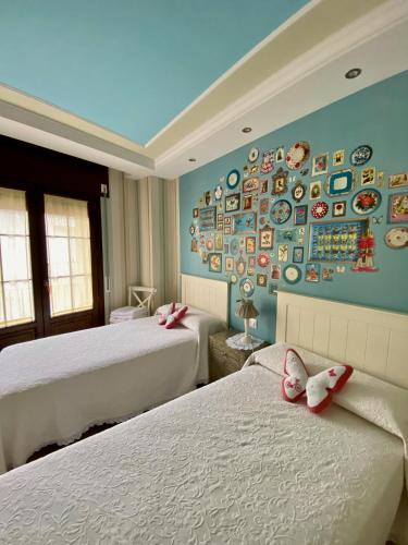 two beds in a room with plates on the wall at Apartamentos Rurales El Rapallo in Alhama de Aragón