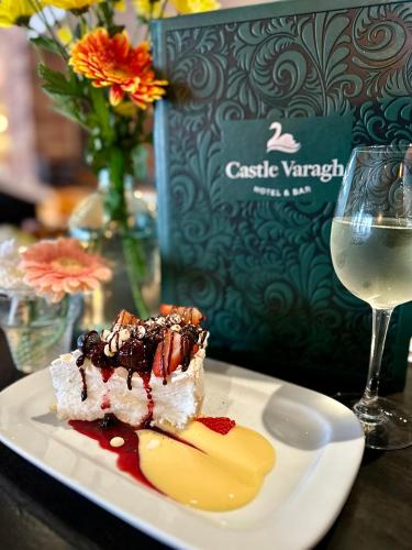 a piece of dessert on a plate next to a glass of wine at Castle Varagh Hotel & Bar in Westmeath