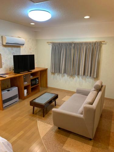 a living room with a couch and a tv at Cottage Village 宿り木荘 in Oga