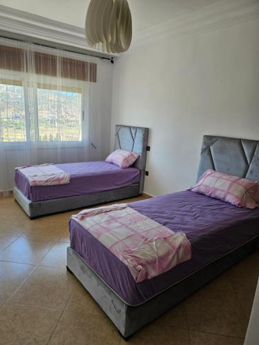 two beds sitting in a room with two windows at Vaste appartement au centre de Tetouan in Tetouan