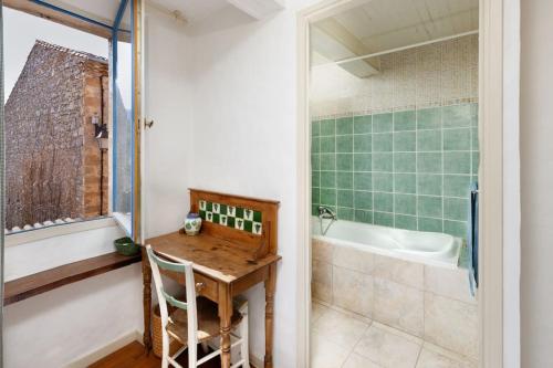 La salle de bains est pourvue d'une table en bois et d'une baignoire. dans l'établissement Villa en campagne avec cour intérieure, à Arques