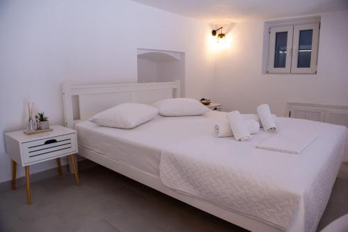a white bedroom with a white bed and a night stand at Ostria kythnos apartment in Kithnos