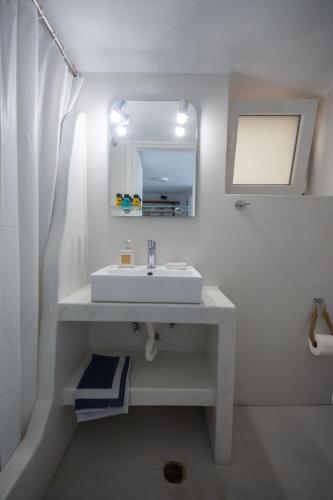 a white bathroom with a sink and a mirror at Ostria kythnos apartment in Kithnos