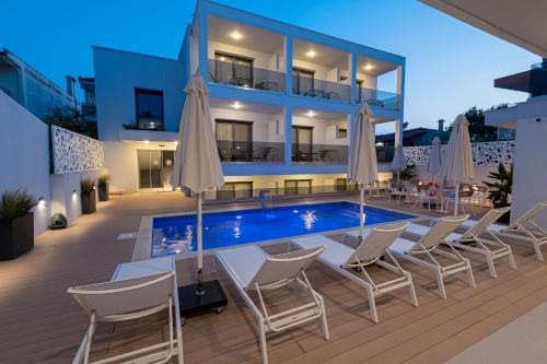 カリテア・ハルキディキにあるElegant Maltepe by Travel Pro Services - Kallithea Halkidikiのスイミングプール(椅子、パラソル付)のある建物