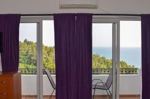 a room with purple curtains and a view of the ocean at Villa Dulsinea in Ulcinj