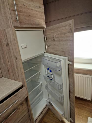 an empty refrigerator with the door open in a kitchen at Apartamentai AKVIJOLA in Vilkaviškis