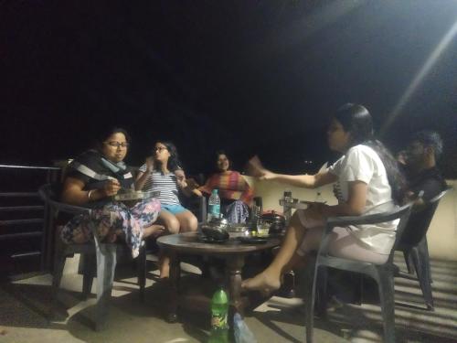 a group of people sitting around a table in the dark at Jitendra home stay in Sari