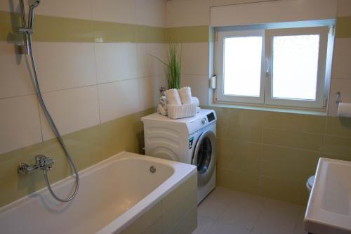 a bathroom with a tub and a washing machine at Apartments Anita Frane in Vodice