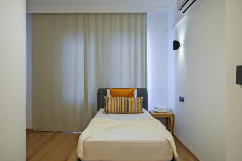 a bedroom with a bed with an orange pillow on it at Körfez Residence in Fethiye