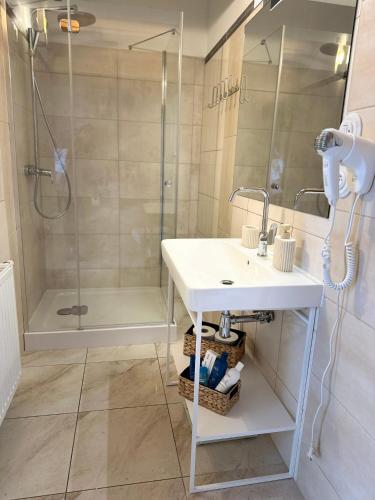 a bathroom with a sink and a shower at Apartament DALBA in Krynica Morska