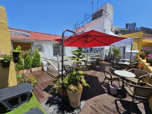 a patio with a red umbrella and tables and chairs at Zaida Boutique Hotel in Seville