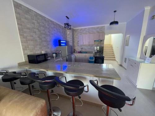 a kitchen with a counter and stools in a room at Mohamed Afifi GAIA Ras El-Hekma - Penthouse 2BR- Families Only in Ras Elhekma