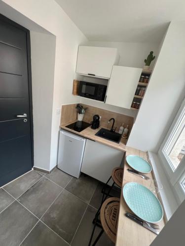 une petite cuisine avec des armoires blanches et un évier dans l'établissement Studio cosy cœur de ville, à Vienne