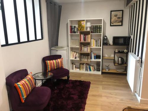 un salon avec deux chaises, une table et une étagère dans l'établissement Agréable studio calme et moderne proche Paris et Arena Défense, à Colombes