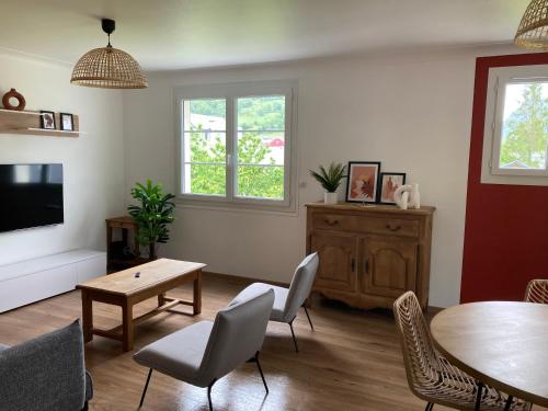 a living room with a table and chairs and a tv at Gîte le Pic du Ger in Laruns