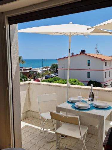 a table and chairs with an umbrella on a balcony at Cerry's Apartments Fronte Mare - Seaside & Sealight in Fossacesia