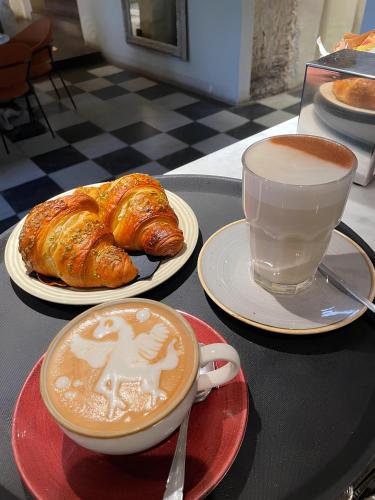 a table with two plates of pastries and a cup of coffee at Palazzo Boyl 1840 in Cagliari
