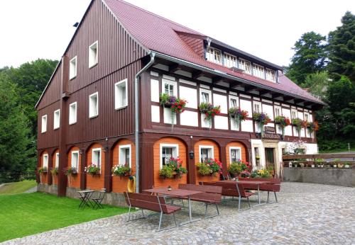 a large building with benches in front of it at Pension Grenzbaude, Waltersdorf, Sachsen in Waltersdorf