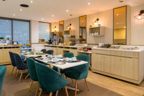 a restaurant with tables and chairs and a kitchen at Best Western Les Bains Hotel et SPA in Perros-Guirec