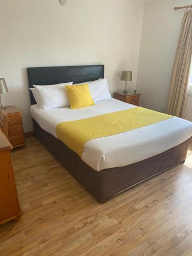 a bedroom with a large bed with a yellow blanket at Doonhill Lodge in Galway