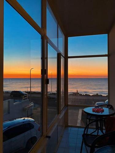 a room with a view of the ocean and a table at entire beachfront apartment 5 Esplanades seaviews in Glenelg