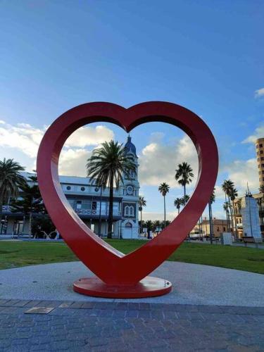 a red heart statue in front of a building at entire beachfront apartment 5 Esplanades seaviews in Glenelg