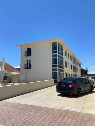 a car parked in a parking lot in front of a building at entire beachfront apartment 5 Esplanades seaviews in Glenelg