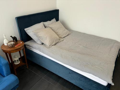 a bed with a blue headboard and a side table at Studio Bleu in Obernai